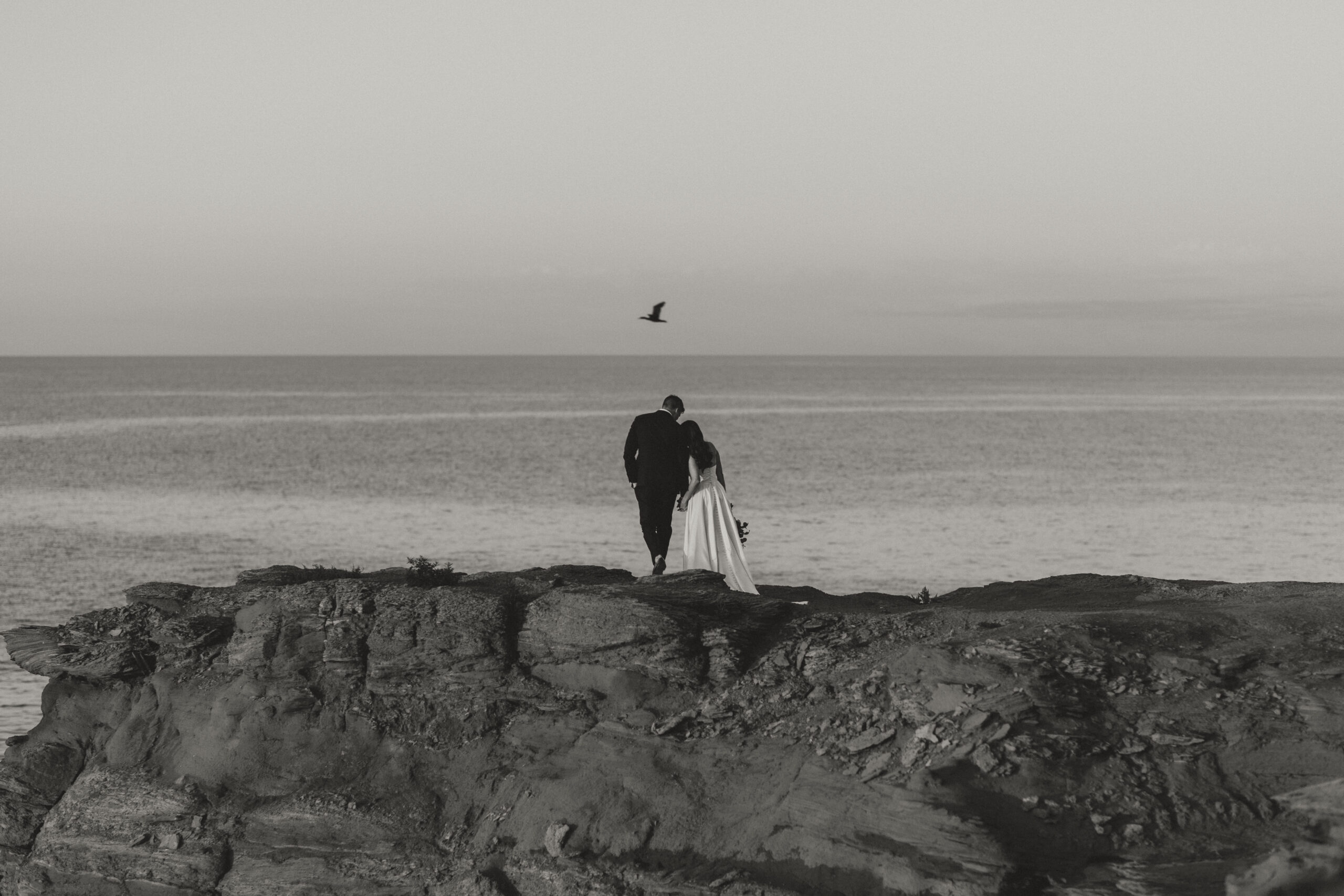 bride and groom walking together looking out at ocean