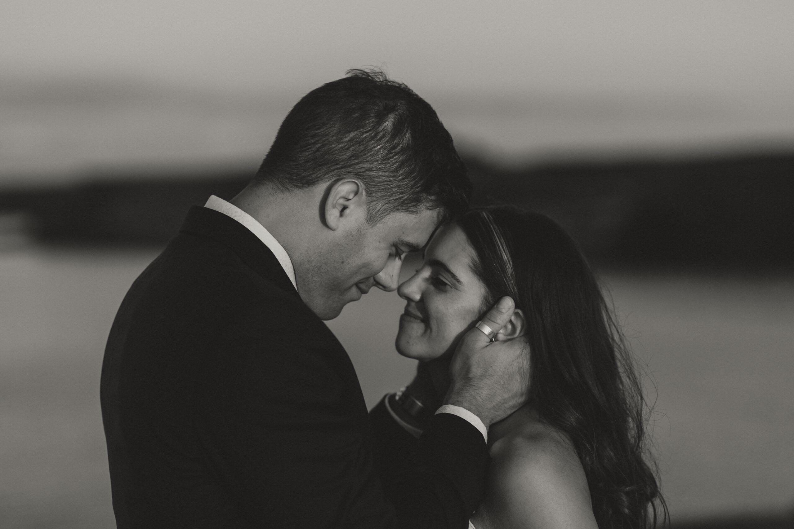 groom holding brides face while forehead to forehead