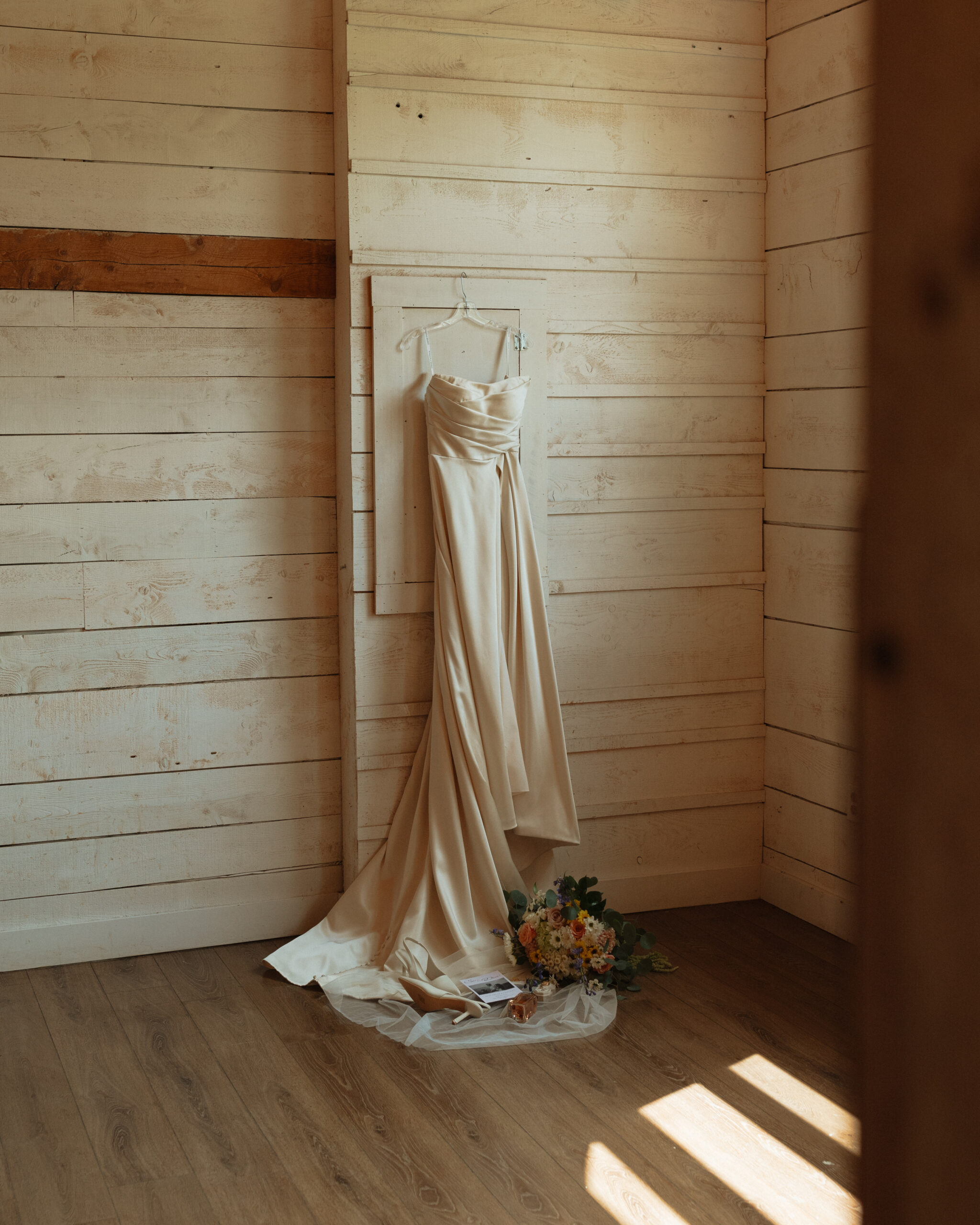 wedding dress hanging on wall with details below at the new London carriage house in PEI