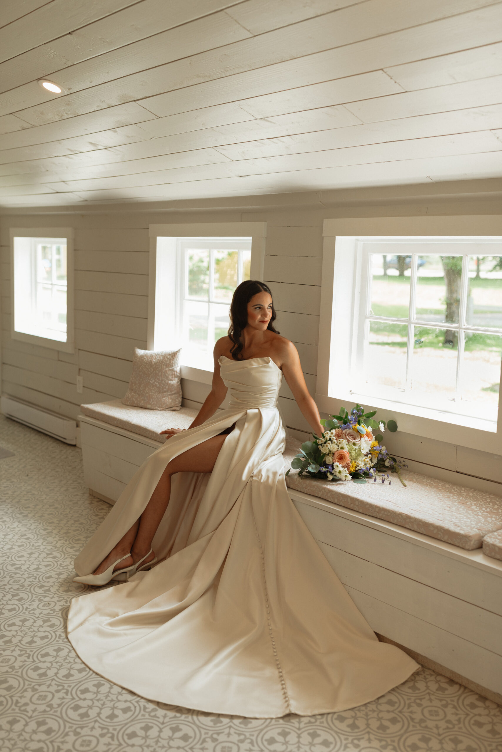  bride sitting in dress looking out window at New London carriage house in PEI