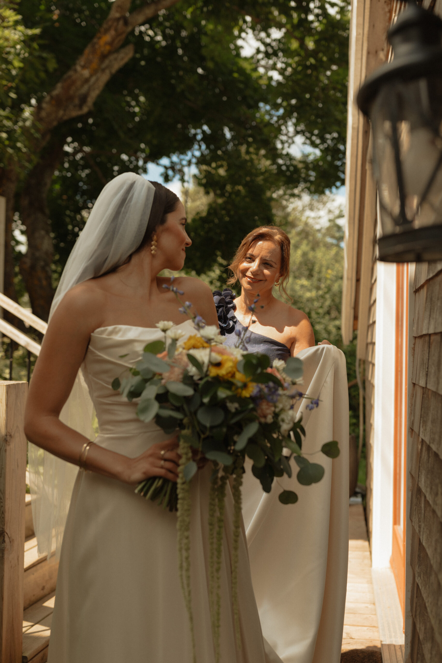 bride looking back at mom smiling at New London carriage house in PEI