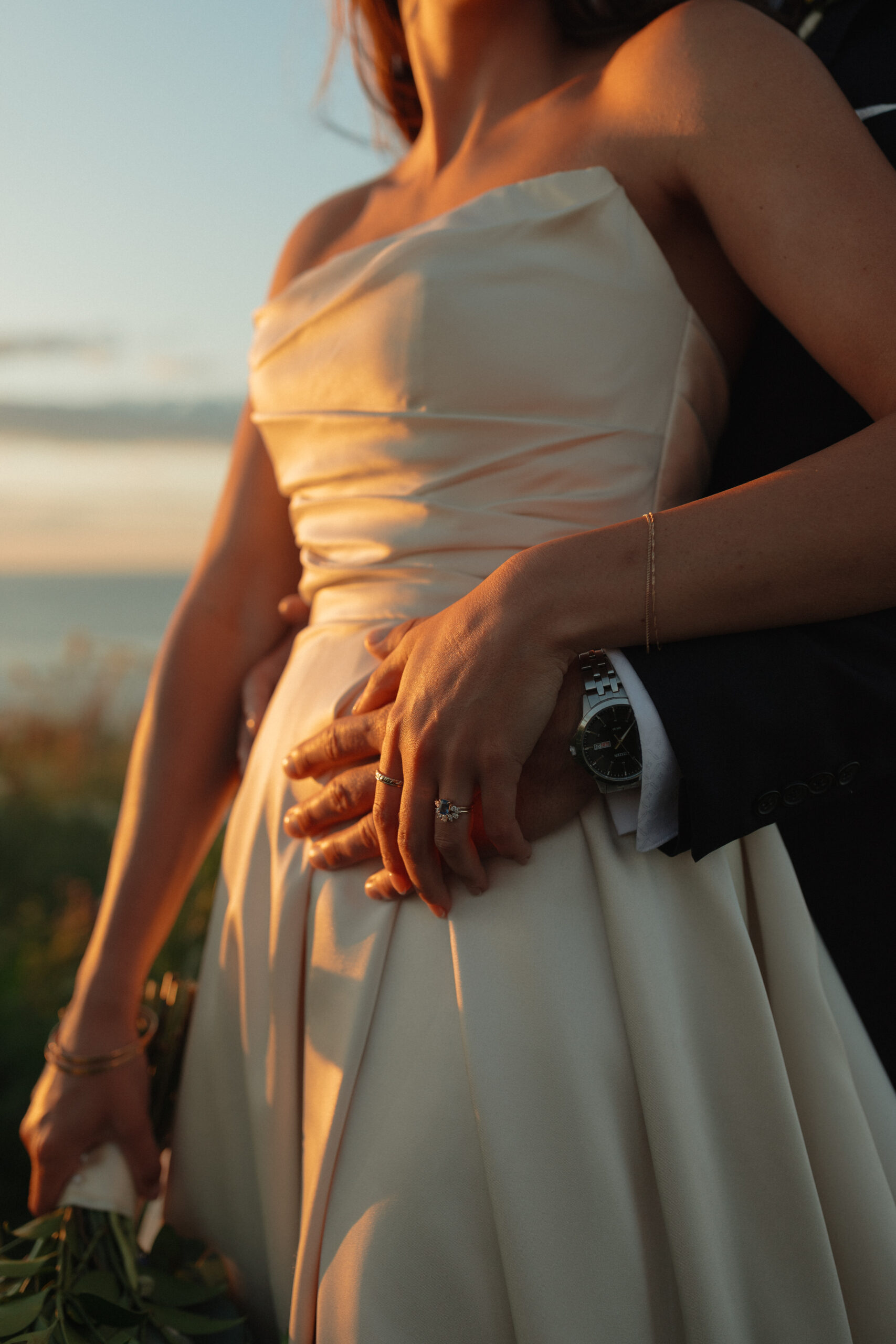 close up of bride and groom hands in the sunset