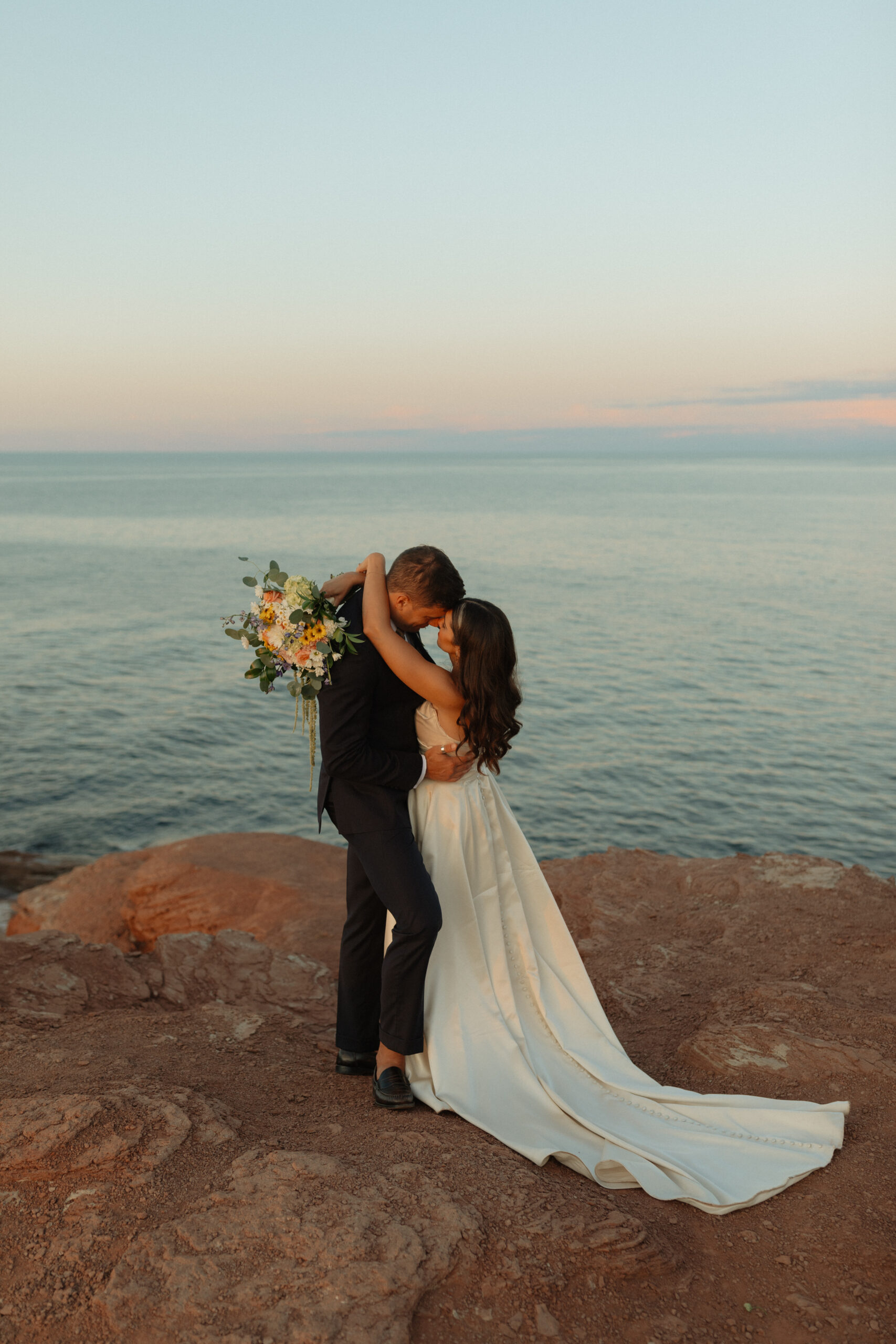 bride and groom dancing on cliff at sunset 