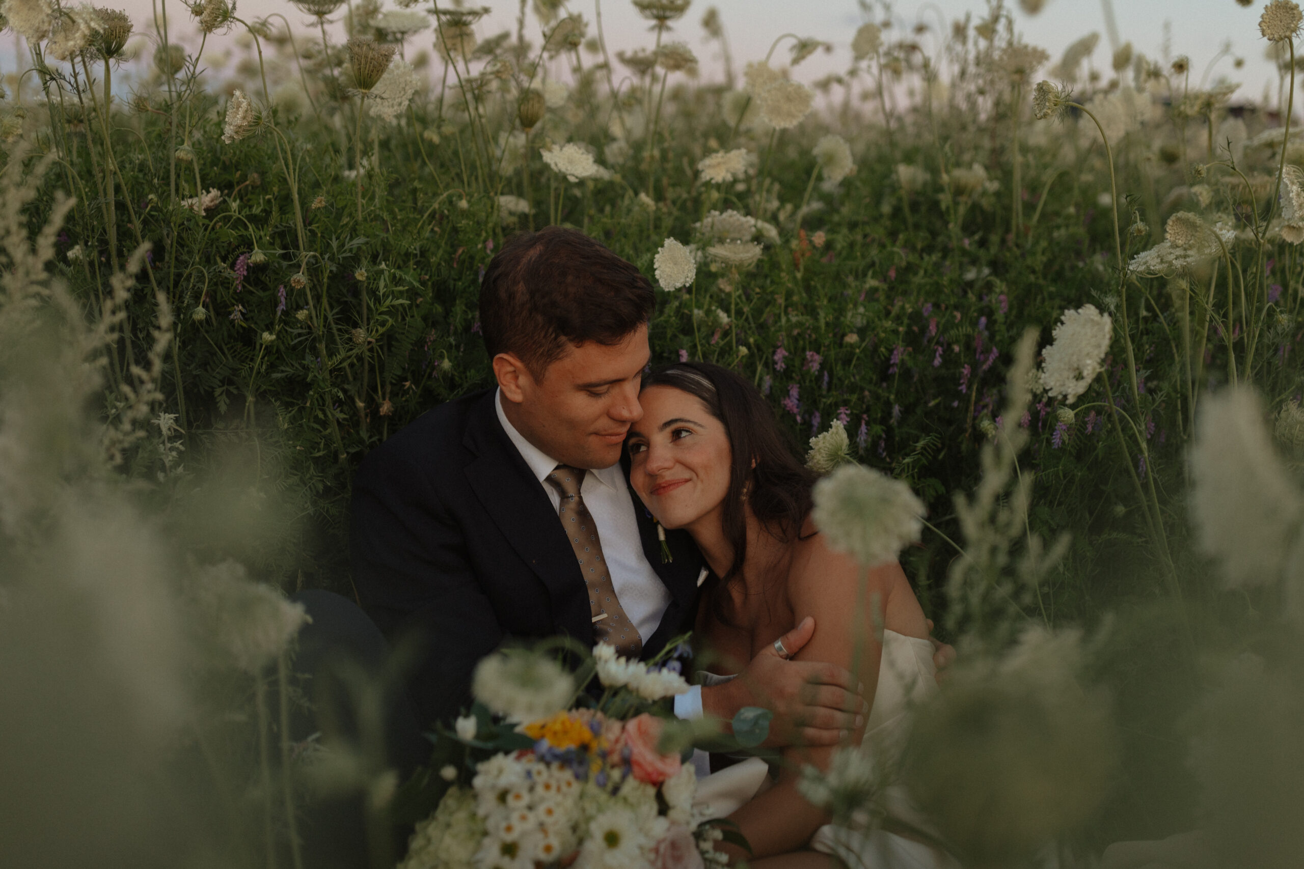 bride and groom sitting in long grass