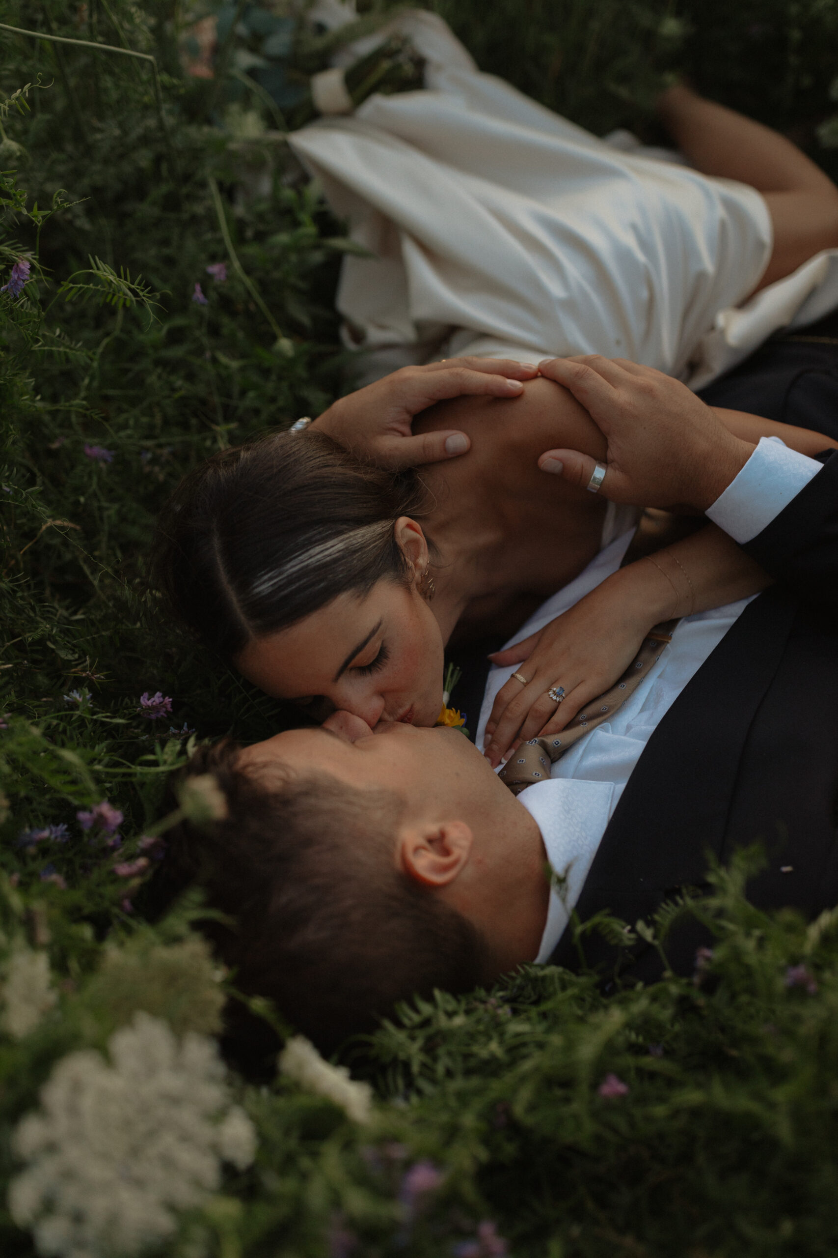 bride and groom kissing while laying in long grass