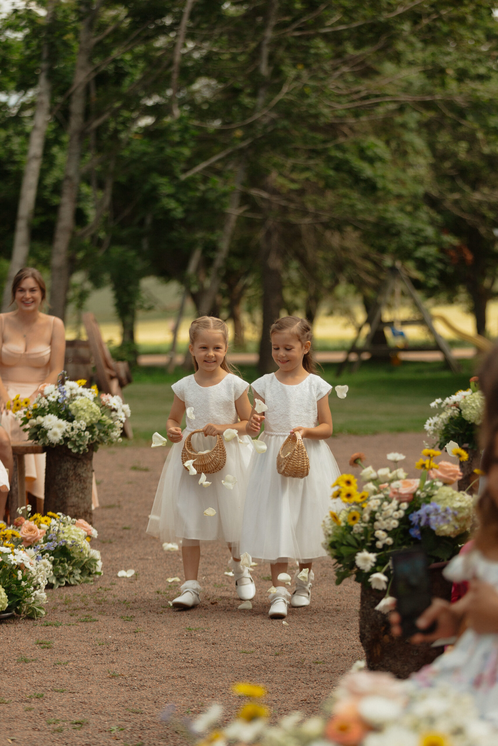 flower girls walking up the aisle while throwing flower petals