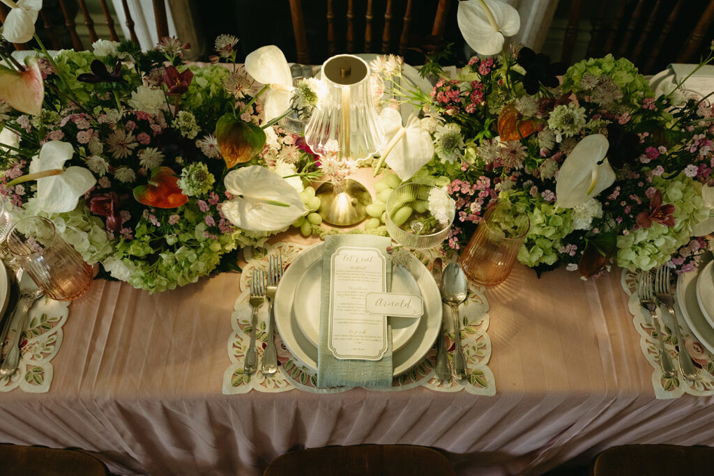 photo of place setting on wedding dinner table with plates, menu, name card, lamp, flowers