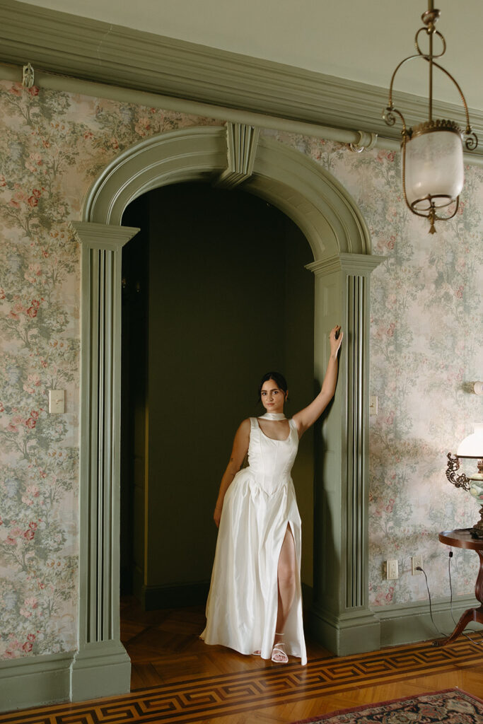far away photo of bride leaning against arched doorway inside fairholm boutique inn