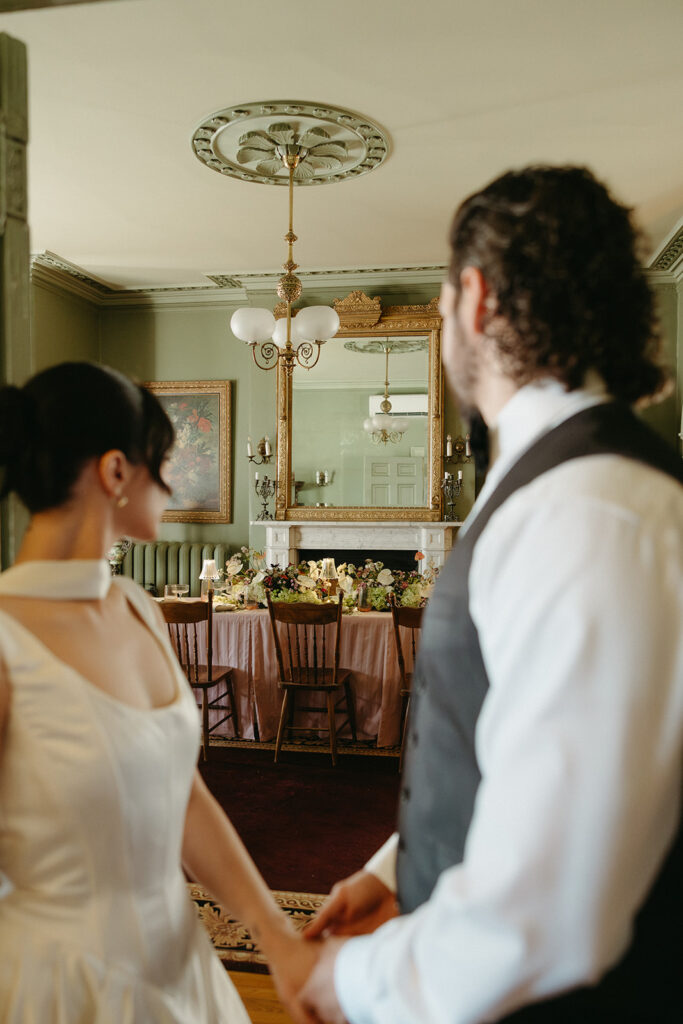bride and groom holding hands overlooking wedding dinner table setup inside fairholm inn