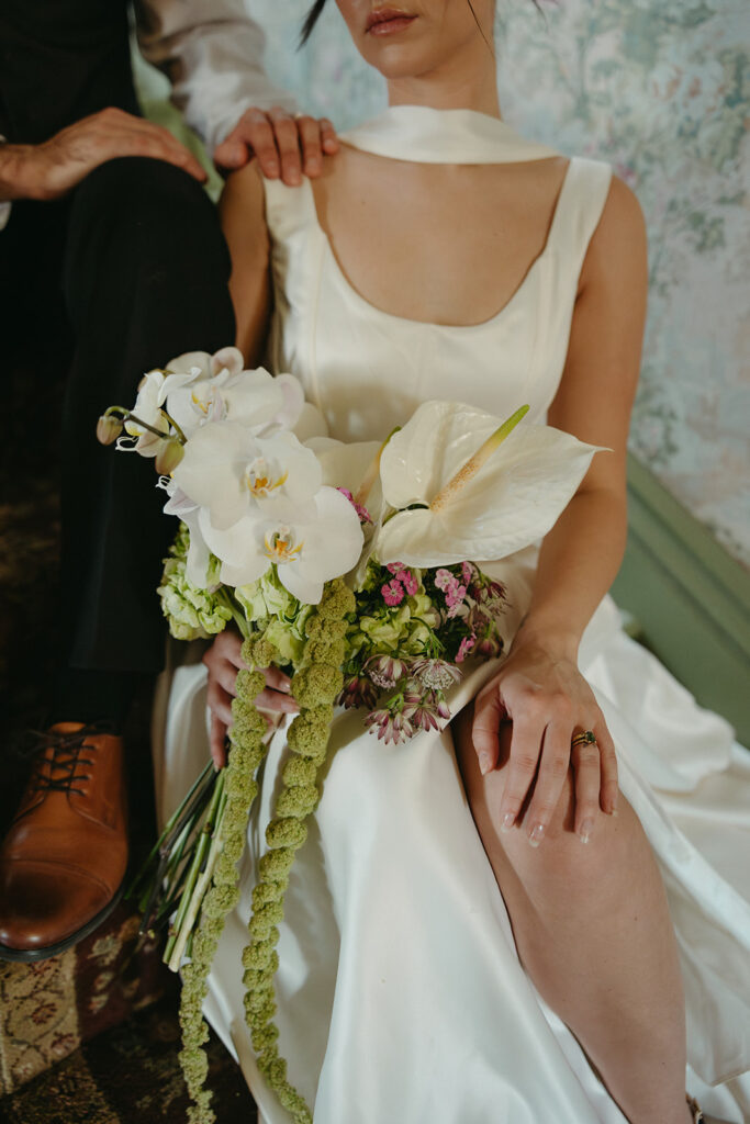 bride and groom sitting on stairs, close up photo of bridal bouquet