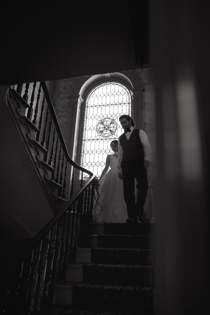 black and white photo of bride and groom walking down the stairs inside vintage inn