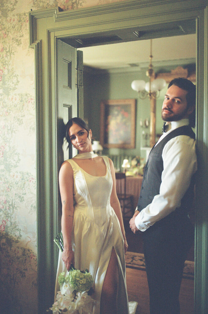 film photo of bride and groom leaning against opposites sides of doorway in fairholm boutique inn