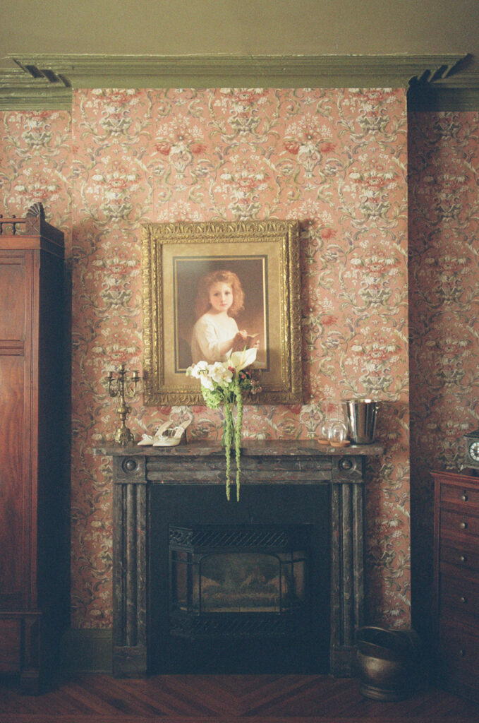 film photo in fairholm boutique inns of haunted child portrait over the mantle with bridal bouquet and shoes sitting on mantle