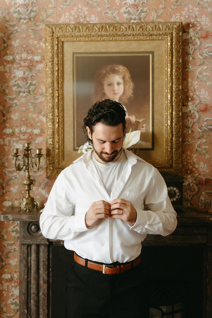 groom buttoning up shirt 